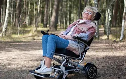 Dam som vilar i en Airgo S3 elrullstol i skogen